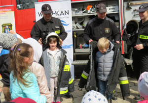 Dzieci przymierzają strój strażacki.